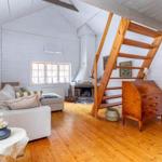 Wohnzimmer mit Sofa, Kamin und Holztreppe zu einer oberen Etage.