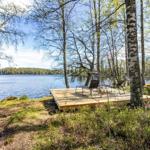 Holzterrasse mit Liegestühlen am See, umgeben von Bäumen.