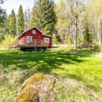 Rotes Holzhaus mit Veranda in grüner Umgebung