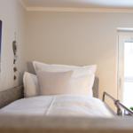 Ein Bett mit weißen Kissen und einer Bettdecke. An der Wand hängt ein großes Wandbild.