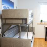 Zimmer mit Doppelstockbett, Schreibtisch und Fenster