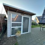 Eine Sturmhaube mit Glasfront und Holzverkleidung auf einer Terrasse.