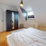 Schlafzimmer mit Dachschrägen, Bett, Kleiderschrank und Fenster.