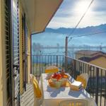 Terrasse mit Tisch und Stühlen, Blick auf See und Berge.