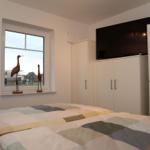 Schlafzimmer mit Bett, Fenster, Kleiderschrank und Fernseher.