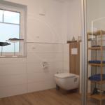 Badezimmer mit Toilette, Dusche und Fenster mit Vogeldekoration.