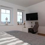 Schlafzimmer mit Bett, Schreibtisch, TV und zwei Fenstern.