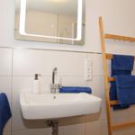 Badezimmer mit Waschbecken, Spiegel und Handtuchständer.