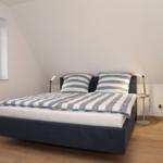 Schlafzimmer mit Doppelbett, Fenster und Schrank.