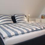 Schlafzimmer mit Doppelbett, Nachttisch und Kleiderschrank.