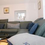 Ein Wohnzimmer mit einem grauen Sofa, einem runden Tisch und einer Lampe.