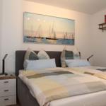 Schlafzimmer mit Bett, Nachttisch und Wandbild mit Segelbooten.