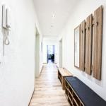 Flur mit Holzboden, Wandtelefon und Holzbank mit Hakenwand.