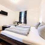 Zimmer mit zwei Betten, Fernseher und Fenster mit Vorhängen.