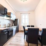 Küche mit Essbereich, Holzboden und Fenster. Schwarze Schränke, Holzoberflächen und Backsteinwand.