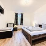 Zimmer mit zwei Betten, Fenster, TV und Holzboden.