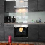 Küche mit dunklen Schränken, Herd, Spüle und Dunstabzug.