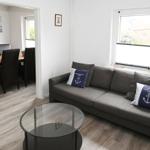 Wohnzimmer mit grauem Sofa, Glas-Tisch und Blick auf Terrasse.