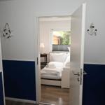 Schlafzimmer mit Blick auf Garten, blaue Wandgestaltung und Schiffsruder-Dekoration.