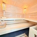 Sauna mit Holzbank, Eiche, Eimer und Deckenbeleuchtung.