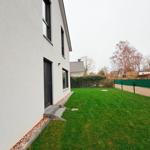 Hinterhof mit Rasenfläche, Eingangstür und Fenstern an der Hauswand.