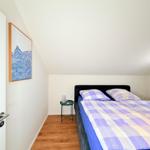 Schlafzimmer mit Doppelbett, Holzboden und Wandbild. Nachttisch neben dem Bett.