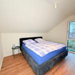 Schlafzimmer mit Doppelbett, Holzboden und Dachfenster. Bett mit blauer Matratze und kariertem Bettbezug.