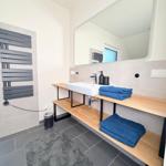 Badezimmer mit Waschbecken, Spiegel, Handtuchhalter und Heizkörper an der Wand.