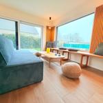 Wohnzimmer mit Sofa, Sitzbank und großem Fensterblick auf Garten