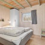 Bedroom with wooden walls, bed, wardrobe, and window with curtain.