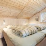 A bedroom with wooden walls, a bed, and a window.