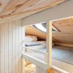 Upper bunk with mattress and window in attic. Lower bunk with mattress.