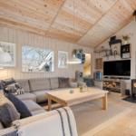 Living room with sofa, fireplace, and TV. Wooden ceiling and floor.