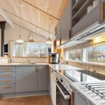 Kitchen with gray cabinets, stainless steel appliances, and wooden ceiling. Large windows with outdoor view.