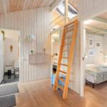 Living area with upper sleeping space, bathroom, and kitchenette. Wooden walls and floor.