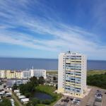 Hochhaus mit Blick auf Meer und Parkplatz. Umgebung mit Hotels und Wohnhäusern.