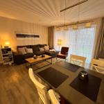 Ein modernes Wohnzimmer mit einem gemütlichen Sofa, einem Sessel und einem Couchtisch. Ein Essbereich mit einem Tisch und  4 Stühlen