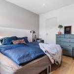 Bedroom with bed, nightstands, and dresser. Single window and mirror visible.