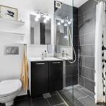Bathroom with shower, sink and toilet. Black tiles and white walls.