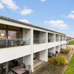 Modern vacation apartment with balcony and terrace. View of green field under blue sky.