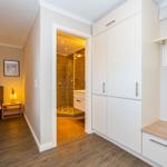 Flur mit Schlafzimmer und Bad. Weiße Schränke, Holzboden und Spiegel.