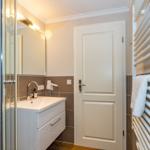 Badezimmer mit Dusche, Waschbecken und Handtuchheizung.