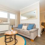 Wohnzimmer mit Sofa, Tisch und Blick auf Schlafzimmer.