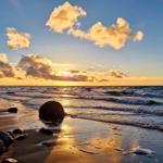 Sonnenuntergang über Meer mit Felsen und Wellen