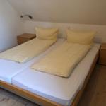 Schlafzimmer mit Doppelbett, zwei Nachttischen und gelben Bettwäsche.