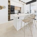 Modern kitchen with island, bar stools, and glass door to terrace.