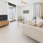 Living room with sofa, TV, and balcony view. Modern furnishings with wooden elements.