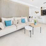 Living room with sofa, tables, and kitchen area in background.