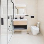 Modern bathroom with shower, sink and toilet. Wall tiles and wooden accents.