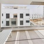 Terrace with white table and bench. View of modern buildings and construction site.